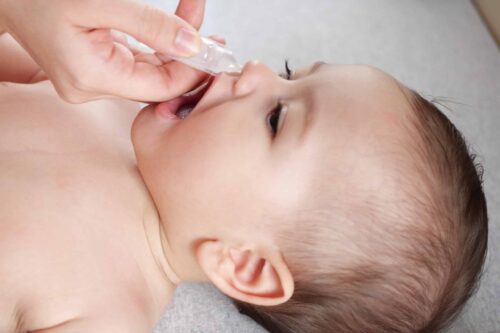 Mother dripping nasal drops for her son. Baby healthcare concept top view